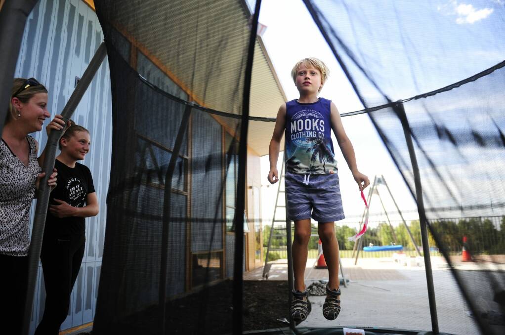 Kayne jumps on the trampoline in the outdoor play area at the Ricky Stuart House in Chifley as his mother Beth and sister Chloe,11, look on.  Photo: Melissa Adams