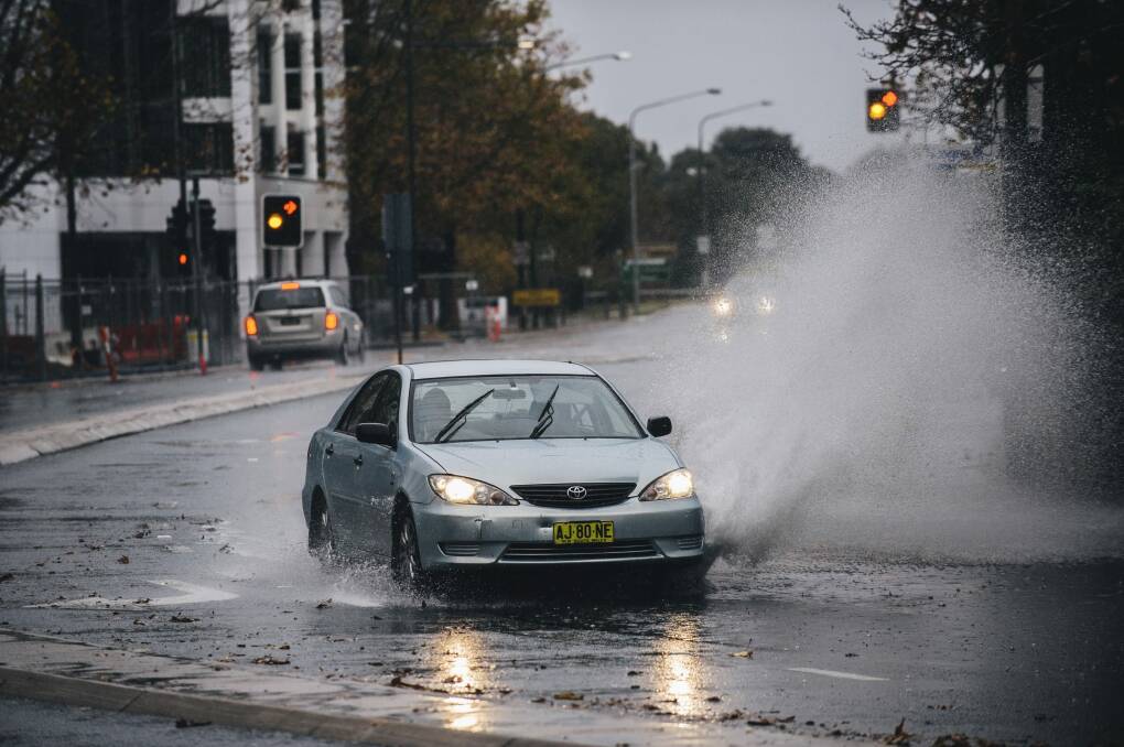 A car passes through water flooded road on London Circuit in Canberra. Photo: Rohan Thomson