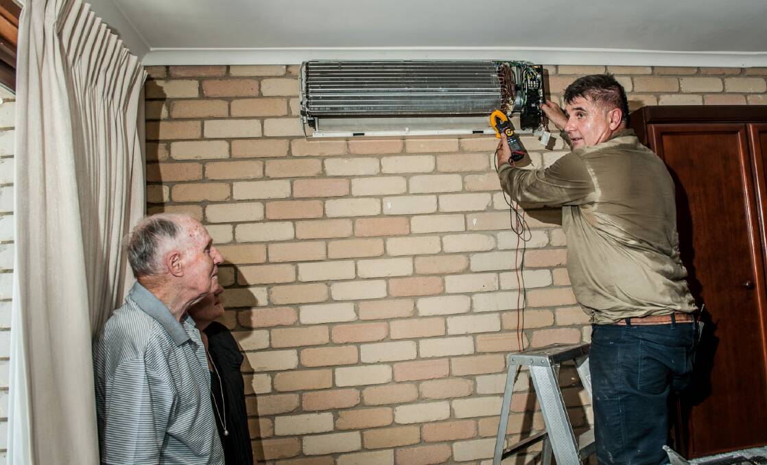 Air conditioning installer Bill Skourtis, right, works in 39-degree heat to help Joe Moore, left, keep cool. Photo: Karleen Minney