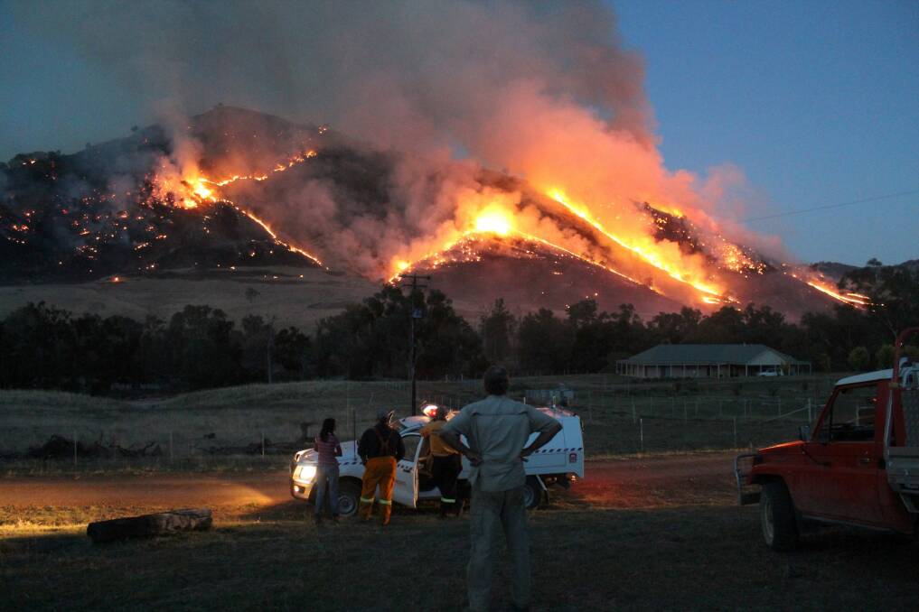 People watch on as a fire burns near Jugiong. A hotter summer this year means an increased risk of fires in the ACT. Photo: Tony Engel
