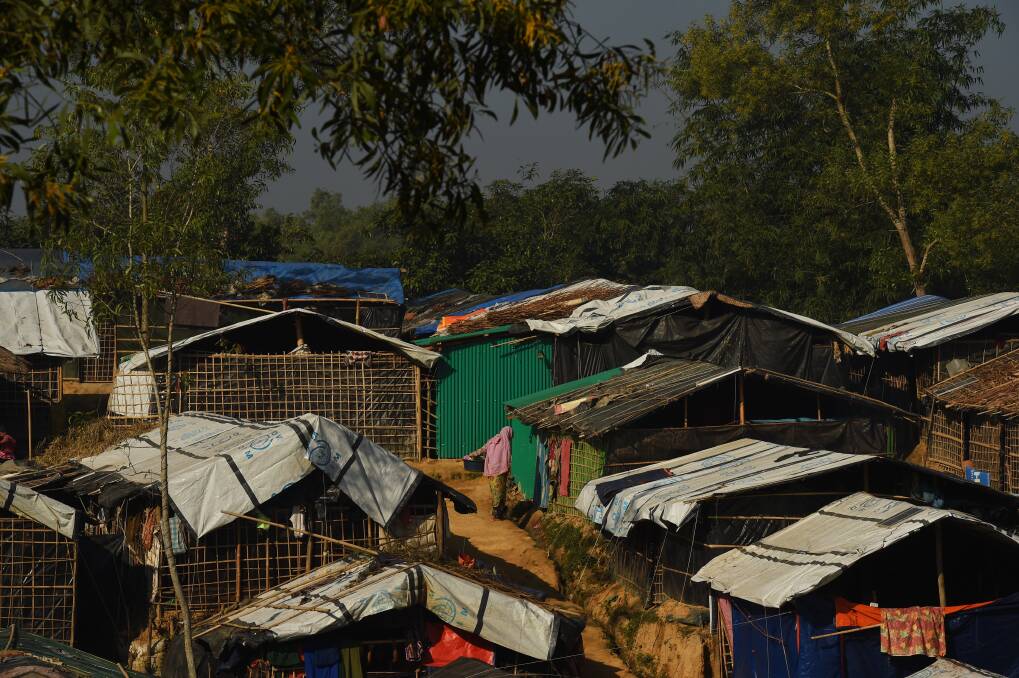 A woman holds a bucket containing clothes as she stands amongst the shelters in Kutupalong refugee camp at Cox's Bazar, home to hundreds of thousands of Rohingya refugees. Photo: Kate Geraghty