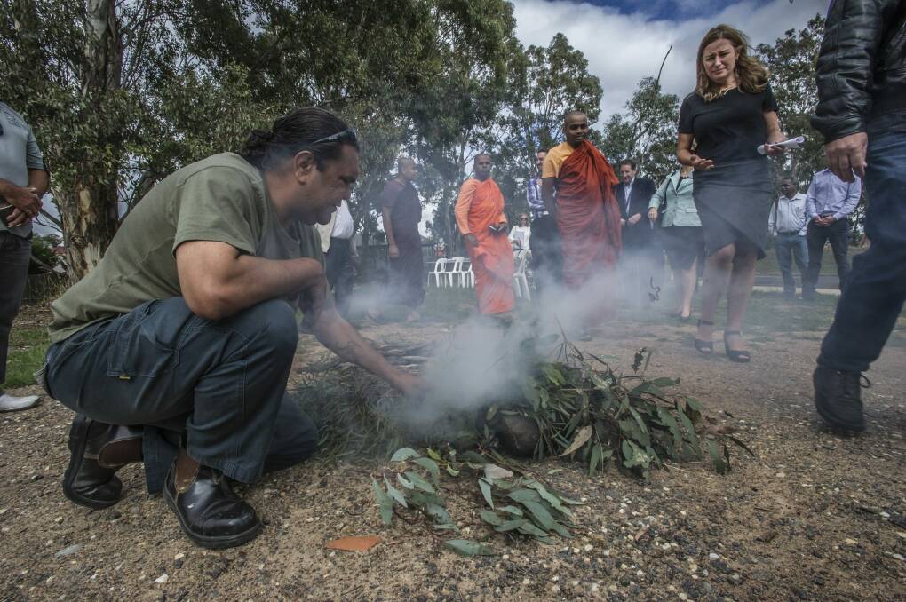 Ranger Adrian Brown conducts the smoking ceremony in Kambah as Housing Minister Yvette Berry walks past. Photo: Karleen Minney