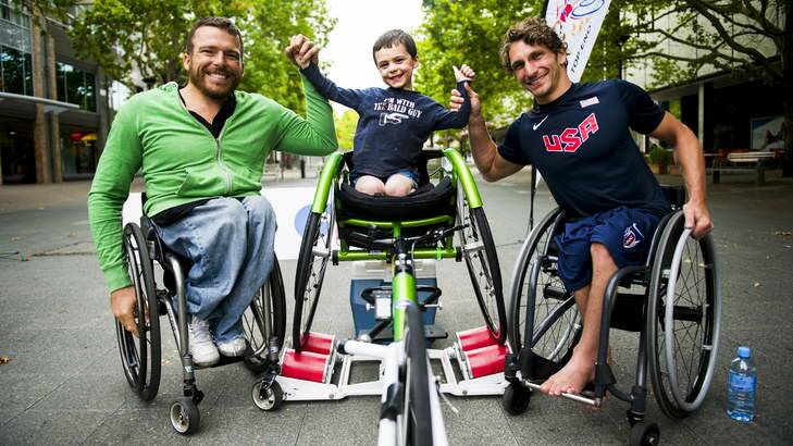 Malcolm Bourke, 5, from Farrer celebrates his wheelchair race performance with athletes, Kurt Fearnley and Josh George (USA), at the race on rollers on City Walk to kick off the Summer Down Under Series on Monday. Photo: Rohan Thomson
