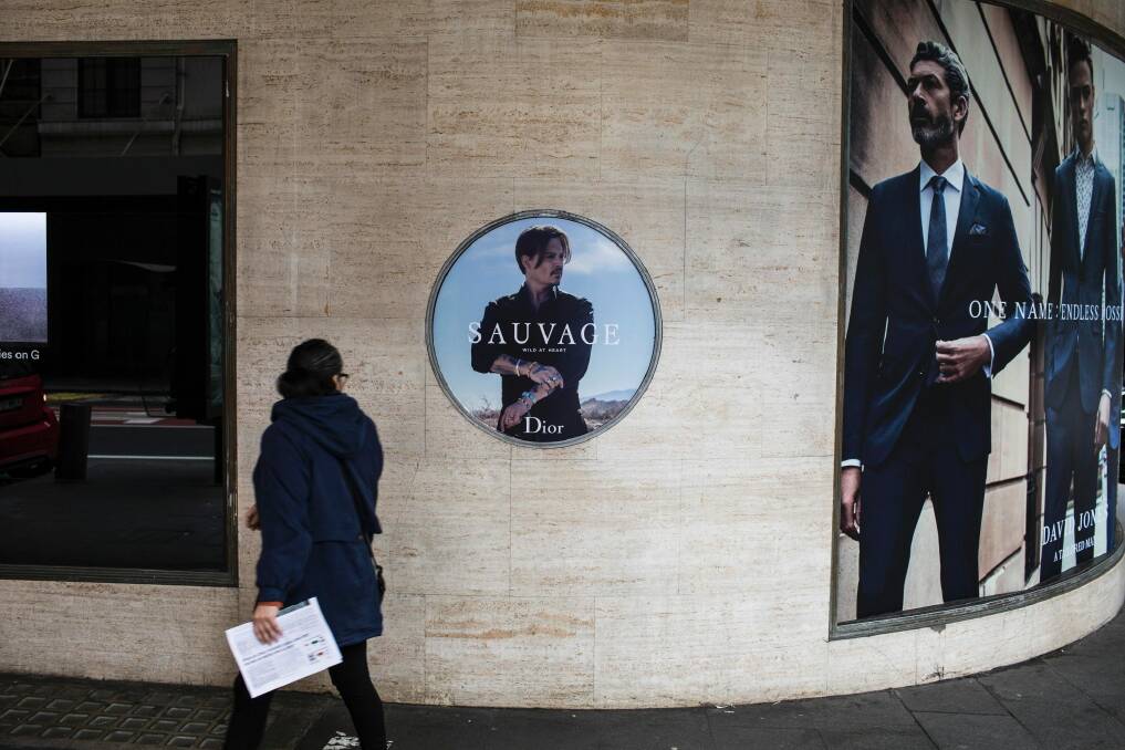 Commuters walk past the Dior Sauvage advertisement featuring Johnny Depp outside David Jones' Sydney CBD store. Photo: Dominic Lorrimer