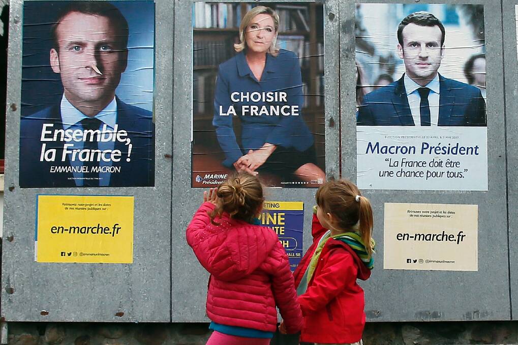 Children walk past election campaign posters in south-west France early last month. Photo: Bob Edme