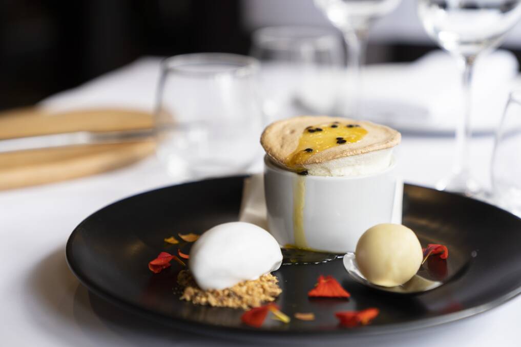 The passionfruit soufflé arrives lofty and proud, with a coconut sorbet and a white chocolate. Photo: Lawrence Atkin