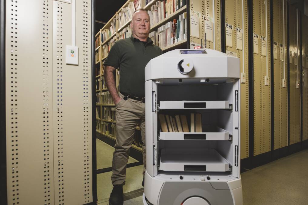 Stack officer Paul Nordern with one of the Isaac robots that traverse the basement levels of the Library carting books and materials around. Photo: Jamila Toderas