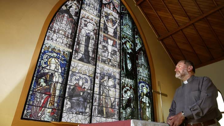 Father Michael Faragher at All Saints Anglican Church in Ainslie in front of a facsimile of the Sheffield Stain Glass Window that has been sent to Queensland to be restored. Photo: Jeffrey Chan