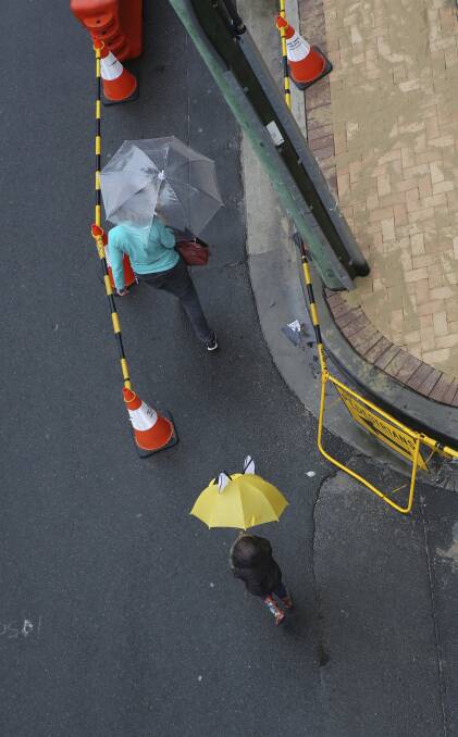 The brollies come out at a construction site in Sydney. Photo: James Alcock
