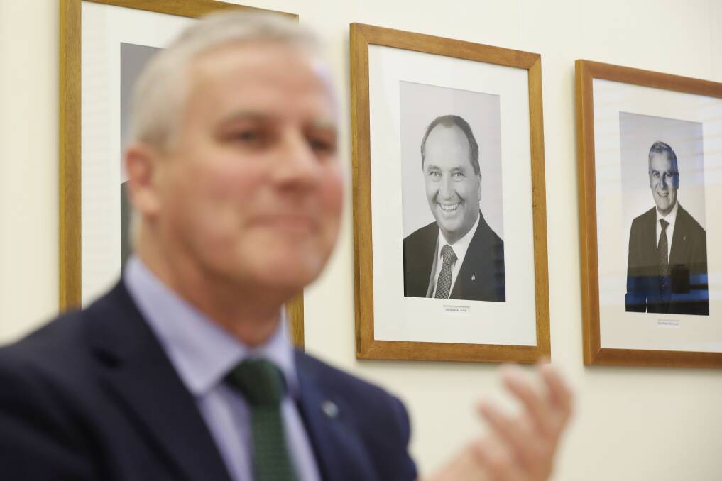 A portrait of former Nationals leader Barnaby Joyce hangs on the wall behind Deputy Prime Minister Michael McCormack. The new party leader has defended the Coalition's commitment to decentralisation.  Photo: Alex Ellinghausen