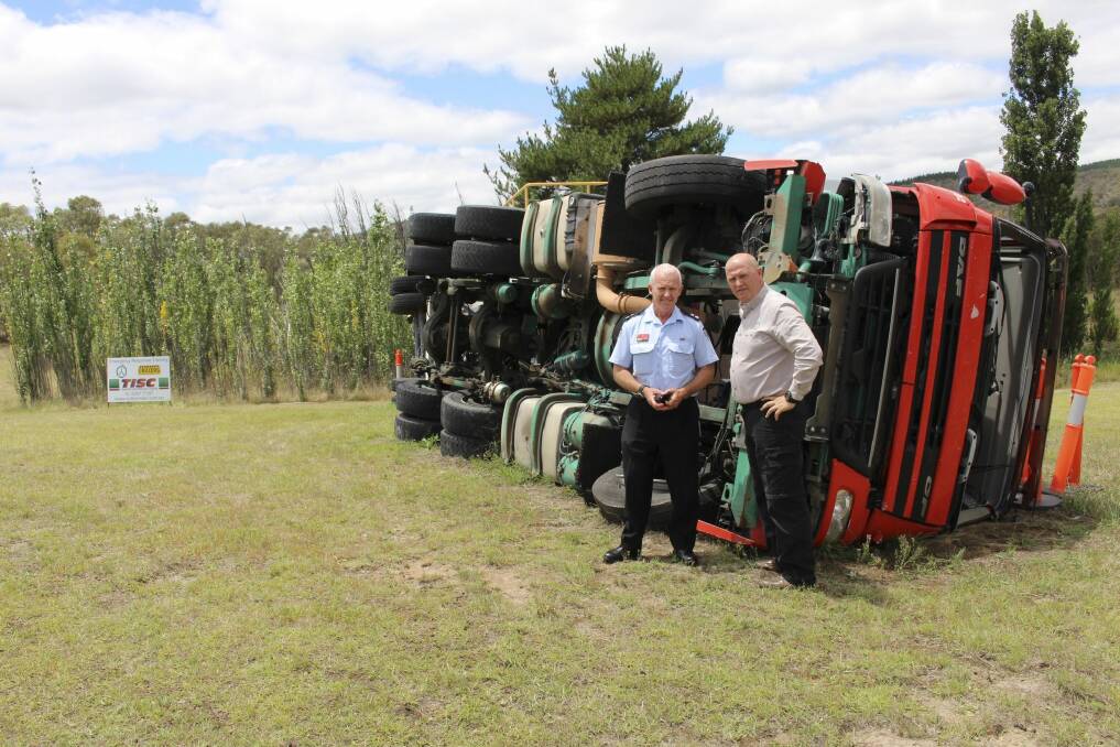 Fire and Rescue NSW Superintendent Kim Reeson and Transport Industries Skills Centre chief executive Ken Brennan near a training vehicle overturned. Photo: Supplied