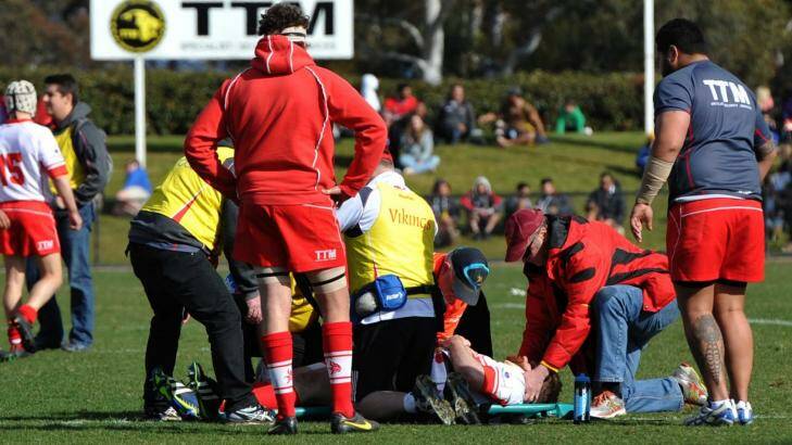 Tuggeranong's Matt Wafer is attended to by medical staff on the field, before being taken to hospital by ambulance. Photo: Graham Tidy