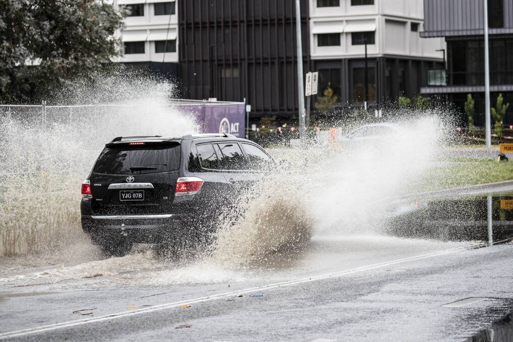 Vehicles navigate local flooding on Wattle Street in O'Connor. Photo: Sitthixay Ditthavong