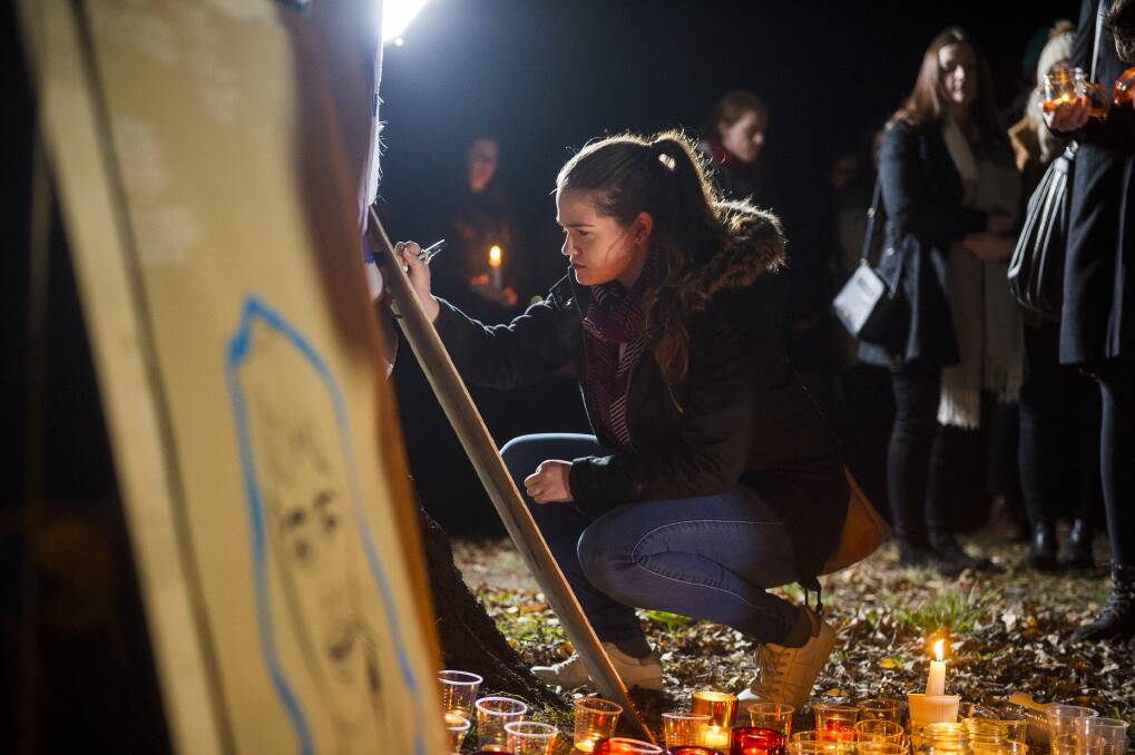 Anna Williams writes a message at the vigil for Eurydice Dixon at Haig Park.  Photo: Dion Georgopoulos