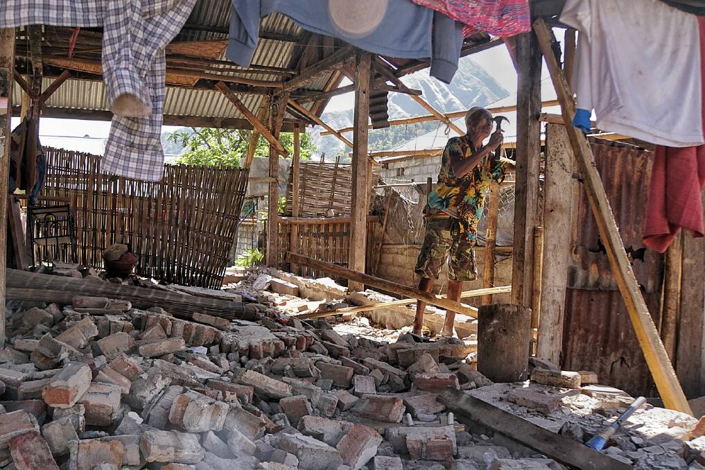 A man tries to fix a roof damaged by the earthquake in Sembalun Bumbung, east Lombok. Photo: Amilia Rosa
