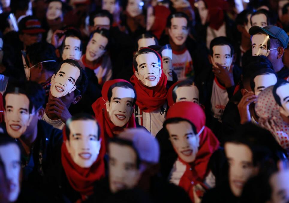 People wear masks depicting Indonesian President Joko Widodo during a rally. Photo: AP