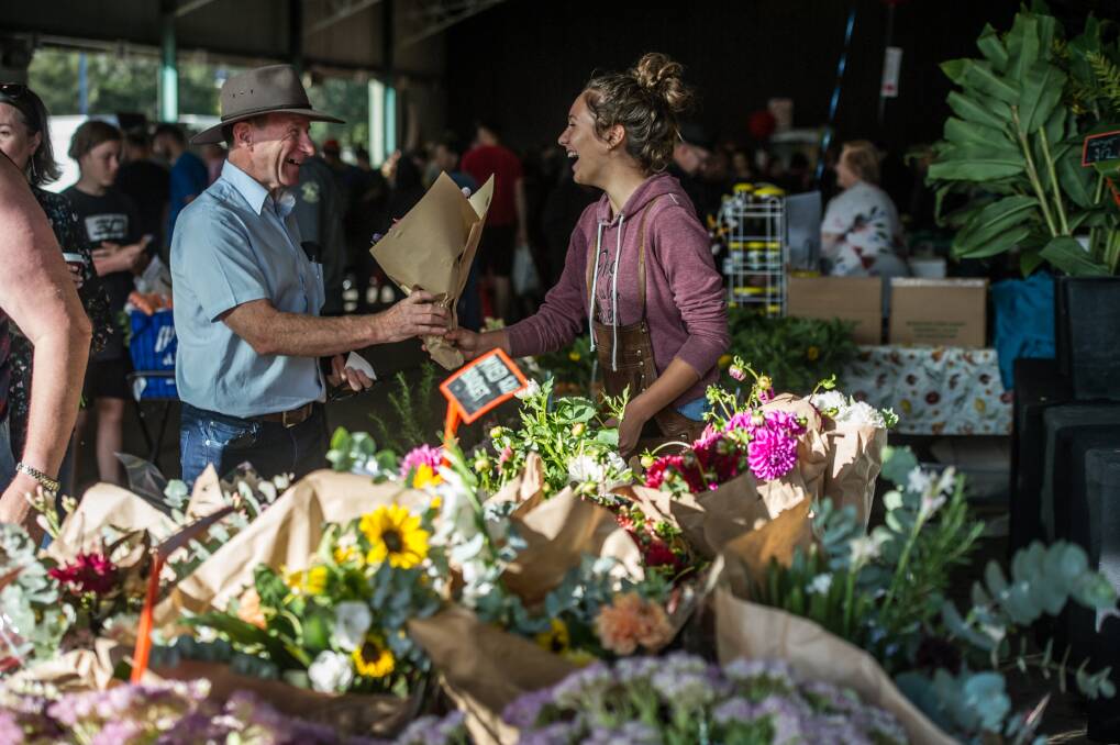 Ed Wensing has shopped at the Capital Region Farmers Market since it began in 2004. Ed bought a bunch of flowers for his wife on Saturday from Nicola Padovano, 16, from Janima Flowers. Photo: Karleen Minney