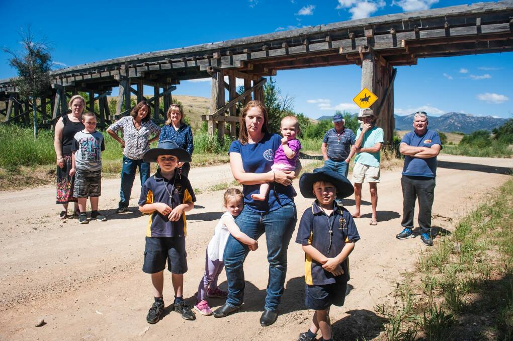 Emily Green, centre, with her children Jack, 7, Neve, 3, Matilda, 11 months and Matthew, 5, with Michelago residents who are unhappy with the NSW Government's consultation over the demolition of the bridge on Micalago Road. Photo: Elesa Kurtz