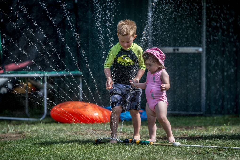 Cooper Bond, 5, and his sister Ivy, 2, of Jerrabomberra play with water in their backyard to cool off during the heatwave. Photo: Karleen Minney