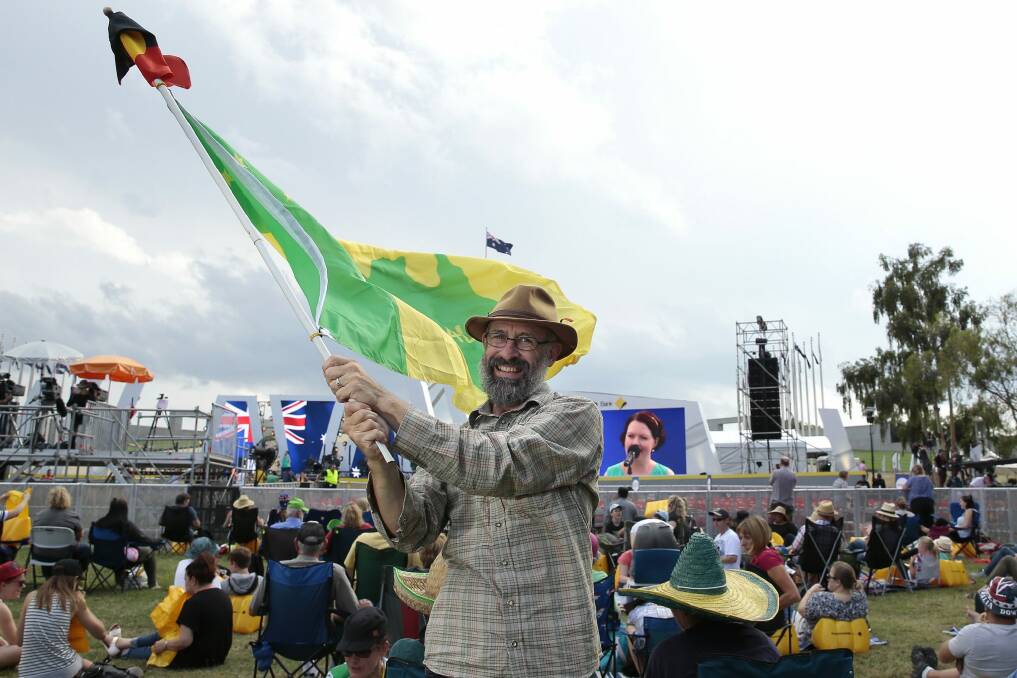 Ian Robertson of Morisset waves the Aboriginal and a Green and Gold flag.   Photo: Jeffrey Chan