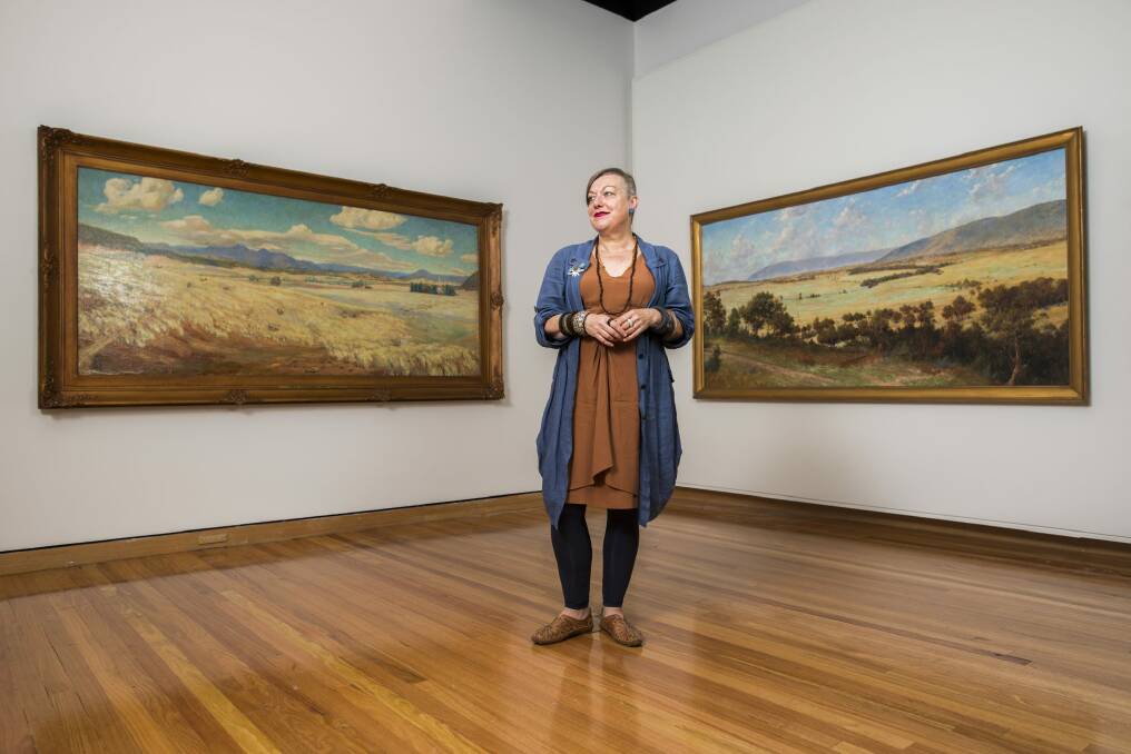 Curator Deborah Clark with two of the four paintings from 1913 of early Canberra. 
 Photo: Rohan Thomson