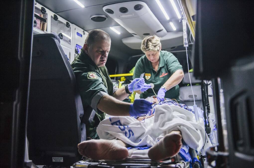 Intensive care paramedics treat a 79-year-old ACT man in the back of an ambulance. Photo: Rohan Thomson.