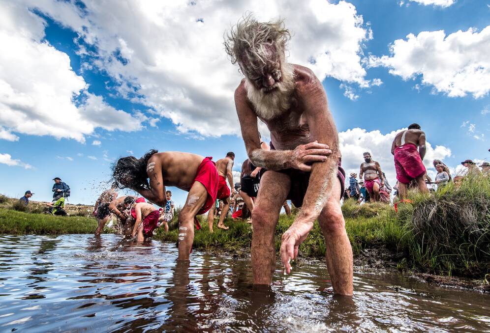 Author Bruce Pascoe (foreground) and other participants in the ceremony wash ochre from their bodies in the Murrumbidgee River. Photo: Justin McManus