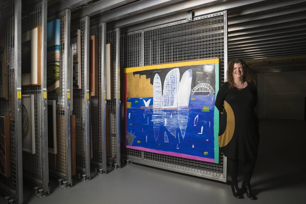 Director of the Parliament House art collection Justine van Mourik shows off a Ken Done painting in the art storeroom. Photo: Sitthixay Ditthavong