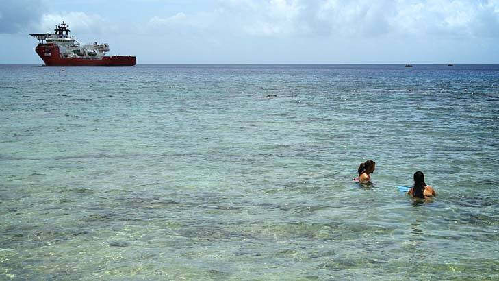Customs vessel Ocean Protector waits in Flying Fish Cove, Christmas Island, as tourists snorkel in the shallow waters. Photo: Wolter Peeters