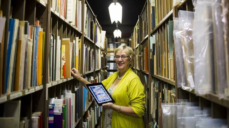 The National Library of Australia's Robyn Holmes in the music stacks holding the NLA's new iPad app called Forte which gives users access to more than 13,000 pieces of sheet music. Photo: Rohan Thomson