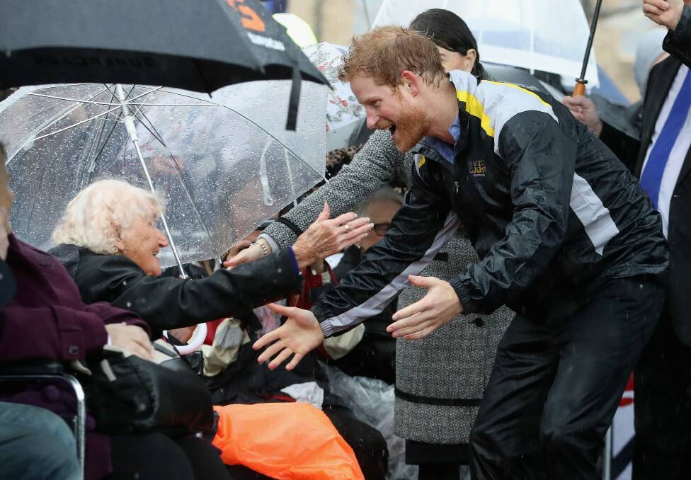 Prince Harry hugs 97-year-old Daphne Dunne during a walkabout in the torrential rain ahead of a Sydney 2018 Invictus Games Launch Event at the Overseas Passenger Terminal. Photo: Chris Jackson