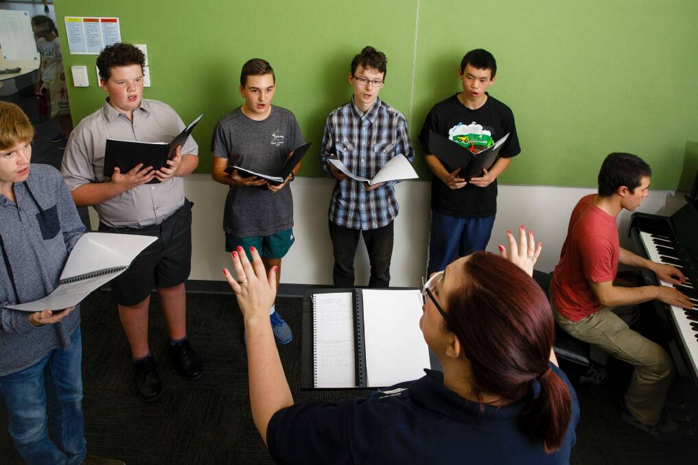 Conductor Rachel Campbell leads members of the Changing Voices choir through a set of vocal exercises. Standing L-R: Tommy Warburton, Oliver Campbell, Caleb Vickers, Ryu Callaway, and Wallace Tan. Accompanying on piano is Lucus Allerton.  Photo: Sitthixay Ditthavong