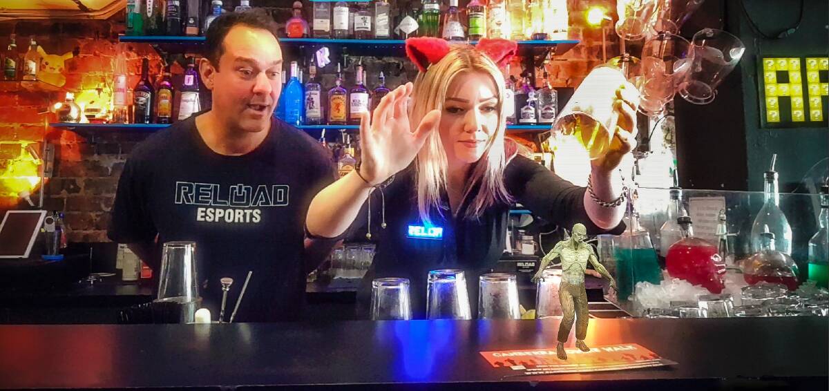 Reload Bar co-owner Ravi Sharma watches manager Hollie Lehmann attempt to catch a zombie with a beer glass in Australia's first augmented reality bar. The scene is photographed on a phone using the bar's app. Photo: Sitthixay Ditthavong