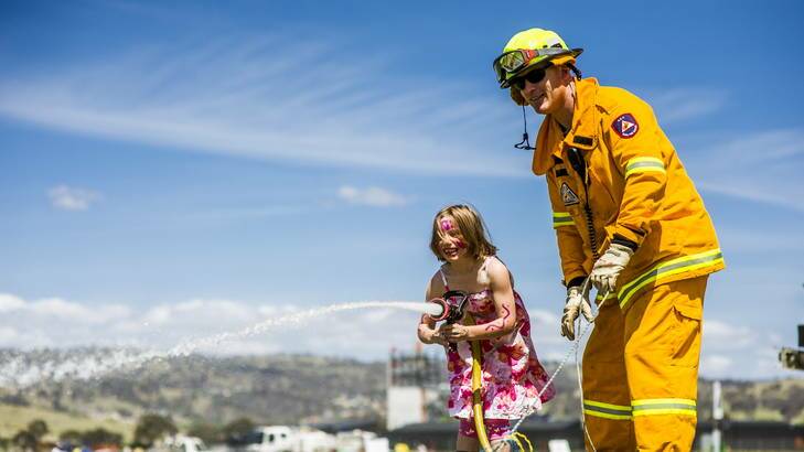 Taya Hoffman, 6, learns how to use a firehose with the help of ACT Rural Fire Service's James Brown. Photo: Rohan Thomson