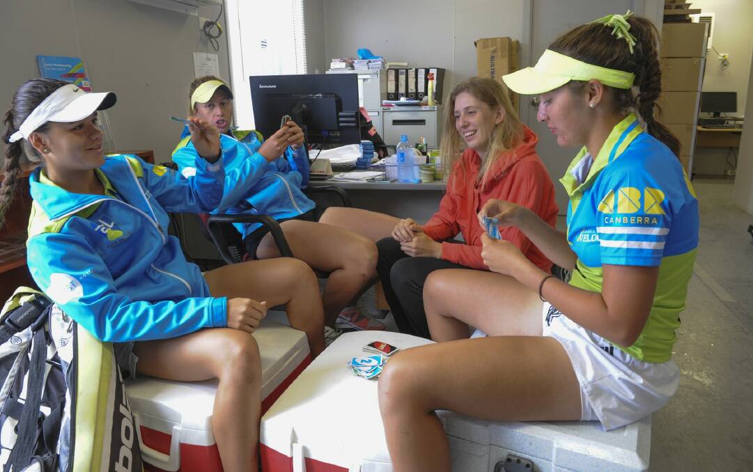 Canberra Velocity tennis players (in blue tops) from left Maria Vais, Tyra Calderwood and Imogen Clews, and Sydney University player, Martina Hudaly (orange top), play cards during a rain delay on Saturday.  Photo: Graham Tidy