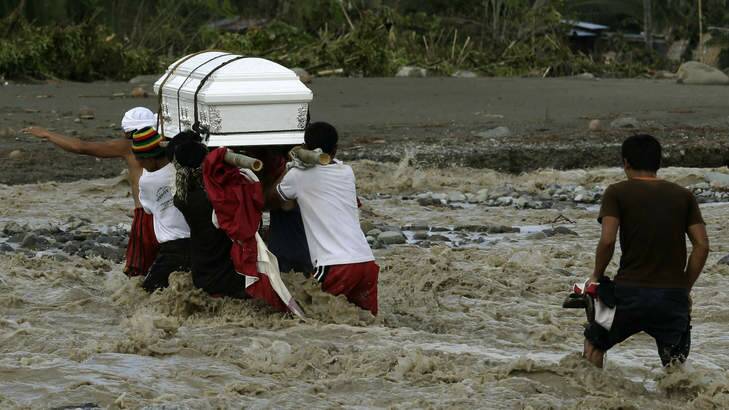 More to come ... Filipinos cross a river to bury a relative, who died in a flash flood caused by a hurricane. Photo: Bullit Marquez