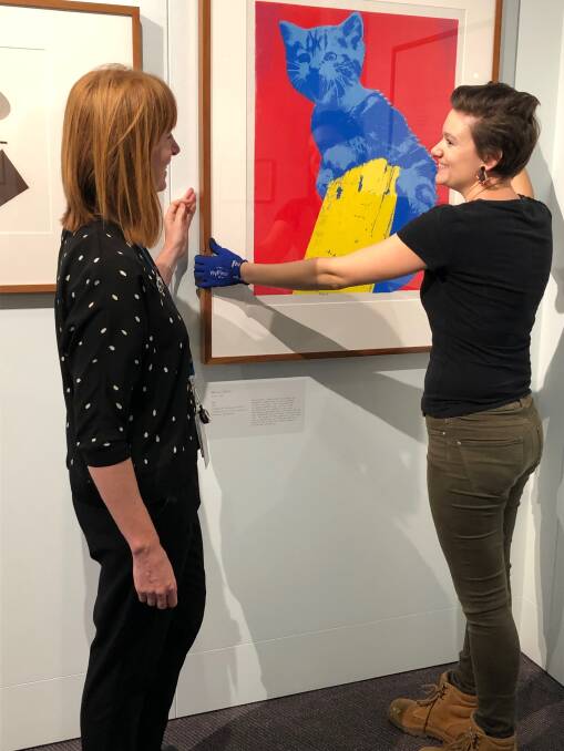 Rebecca Richards, left, and Emilie Patteson,  from the Australian Parliament House art collections team check Meow, a work by Maria Kozic, on display in the Imprint exhibition.  Photo: Supplied
