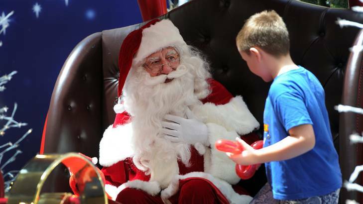 Part-time Santa, at Westfield Belconnen, John Rundle, has his photo taken with eight-year-old Ryan Prichard of Gungahlin. Photo: Graham Tidy