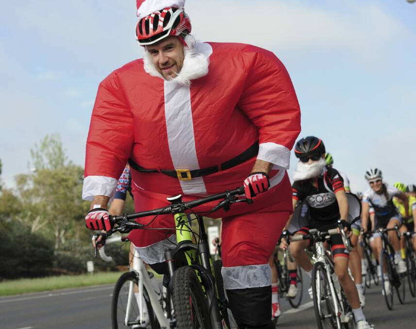 Canberra's Santa (aka Andrew Blair) rides with a group of cyclists past the Lodge on Christmas Day. Photo: Graham Tidy