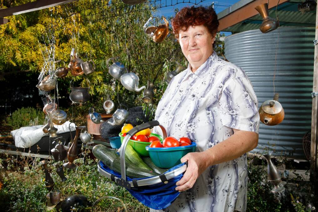 Suzanne Eastwood beside the garden teapot mobile with just harvested tomatoes and zucchini in Rivett. Photo: Sitthixay Ditthavong