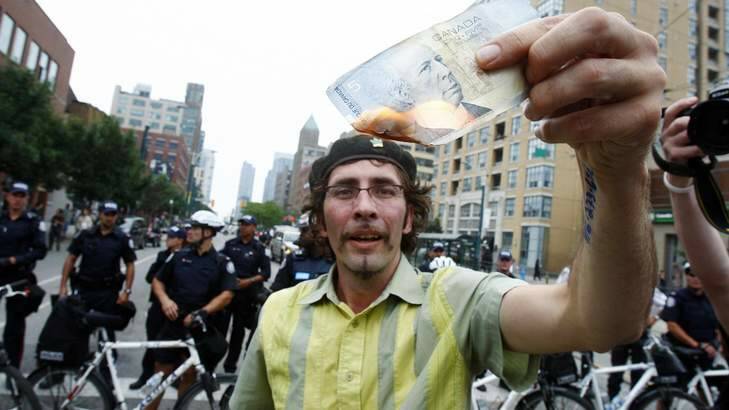 A man burns a Canadian five-dollar note during a protest at the G20 summit in Toronto. Photo: Christinne Muschi