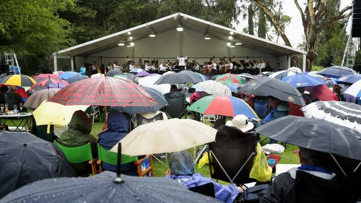 Concert patrons shelter from the rain as the Canberra Symphony Orchestra perform during the Shell Prom Concert on the grounds of Government House. Photo: Jeffrey Chan