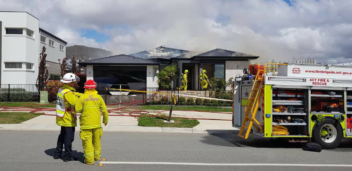 Firefighters at the scene of a blaze that significantly damaged a display home in Kondelea Way, in Denman Prospect. Photo: Emergency Services Agency