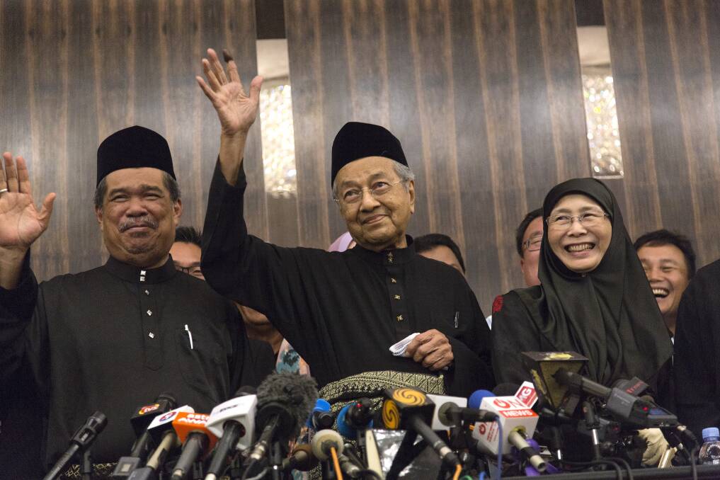 Newly-elected Mahathir Mohamad, centre, waves next to Deputy Prime Minister Wan Azizah, right, in Kuala Lumpur on Friday. Photo: Bloomberg