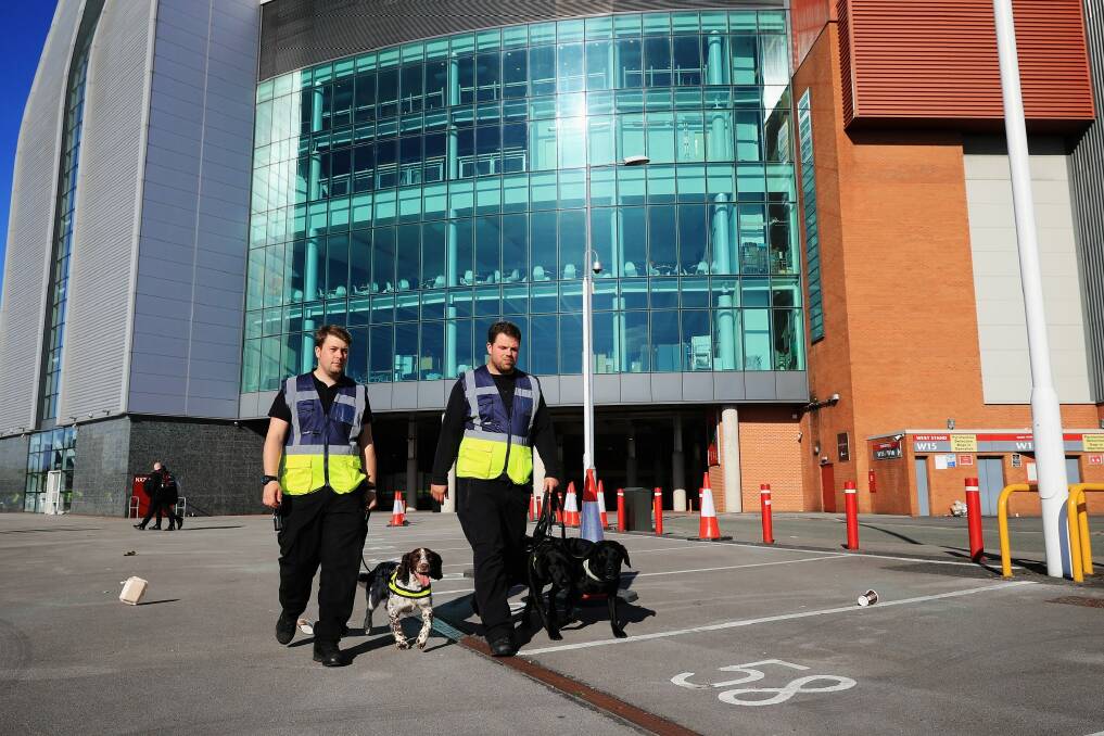 Stewards with sniffer dogs on the scene following a security alert and the abandonment of the Barclays Premier League match between Manchester United and AFC Bournemouth at Old Trafford. Photo: Christopher Furlong