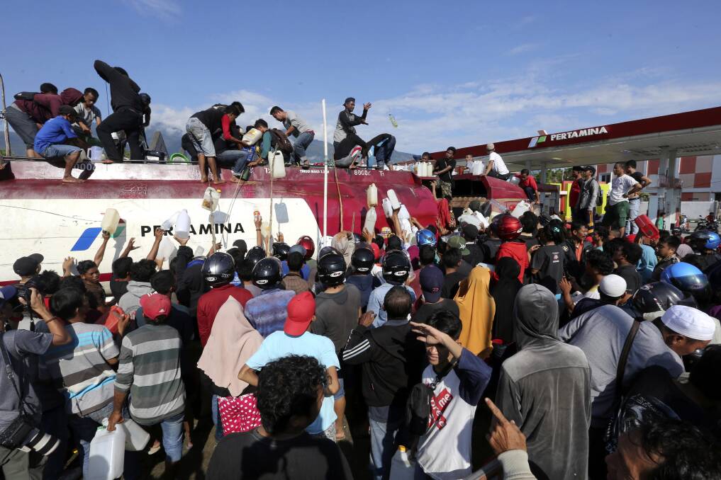 People take fuel from a truck on  Sunday following earthquakes and a tsunami in Palu two days earlier. Photo: AP