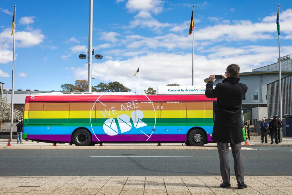 Minster for Road Safety Shane Rattenbury takes a photo of a bus newly painted in rainbow colours in support of marriage equality on Tuesday.  Photo: Sitthixay Ditthavong