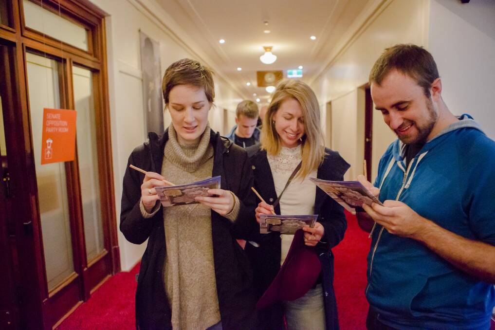 Verity Langer of Lyons, Clare Anderson of Kingston, and Brenden Watts of Kingston enjoy the puzzles on offer while lining up to vote at Old Parliament House. Photo: Jamila Toderas