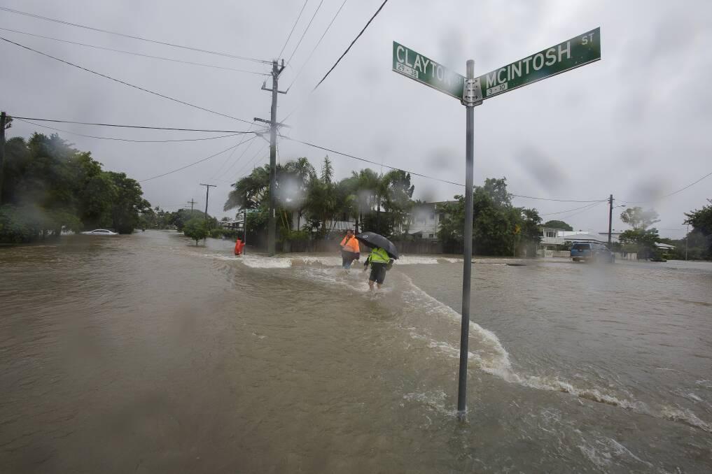 Residents walking through flooded waters in Hermit Park Townsville on Sunday. Photo: AAP