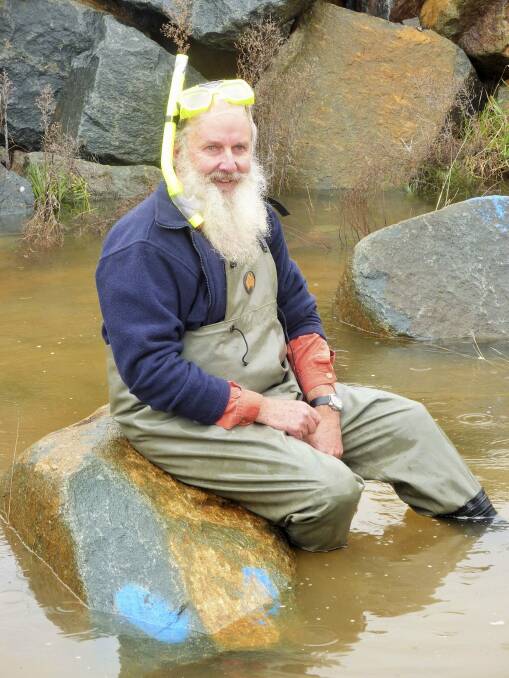 Associate professor Mark Lintermans sits on the nostril of the Cotter Dam's Smiley Face. Photo: Tim the Yowie Man